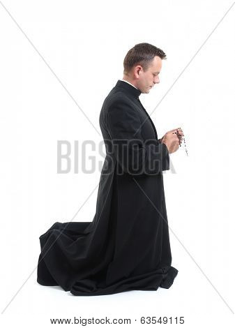 Catholic priest klneeling and saying his rosary beads 