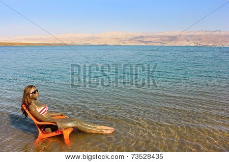 Girl Smeared With Therapeutic Mud Sunbathes, Dead Sea
