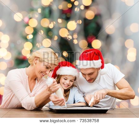 food, family, happiness and people concept - smiling family in santa helper hats with glaze and pan cooking over christmas tree lights background