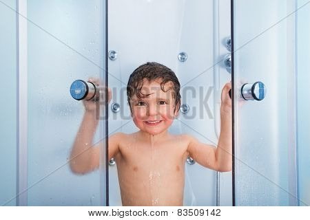 Happy boy in the shower cabin wet and smiling