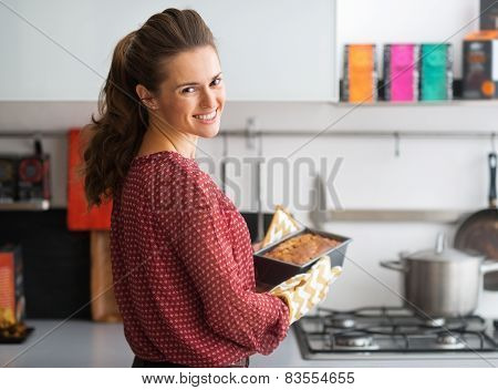 Happy Young Housewife Holding Baking Dish With Bread