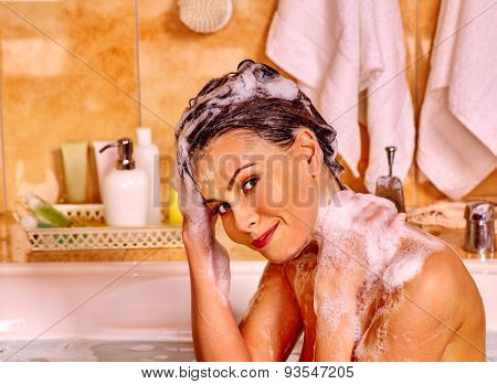 Happy woman washing hair in bubble bath.