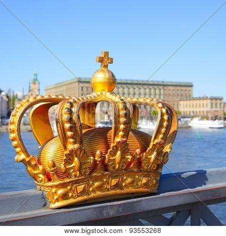 Crown on a bridge railing in Stockholm and Royal Palace in the background, Sweden