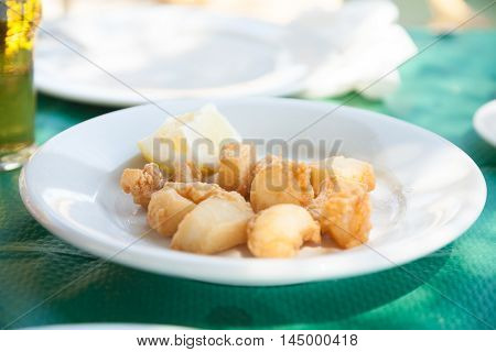 White Dish Of Fried Sepia Pieces On Green Tablecloth