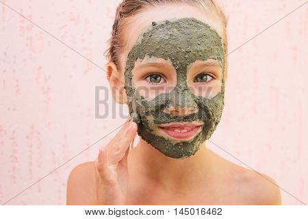 Beautiful young girl with facial clay mask.