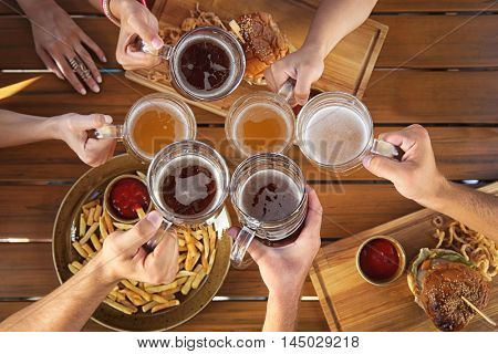 Group of friends drinking beer and eating snacks on wooden background