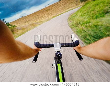 Riding fast on bicycle on asphalt road. Storm in a countryside Original point of view