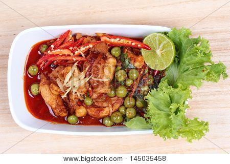 Spicy fried chicken in roasted chili sauce on wood.