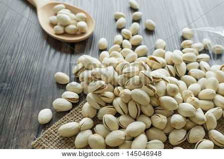Heap of roasted pistachio nuts on wooden background