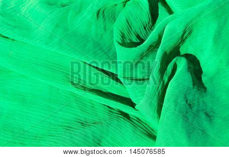 Green fabric abstract background. Chiffon cloth pattern
