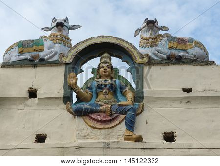 Madurai India - October 19 2013: One blue dressed female guardian or Gana protects the Meenakshi outside wall in the company of two bulls.