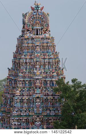 Madurai India - October 19 2013: Closeup of one Vimanam of the Meenakshi Temple against bluish skies. Pastel colors and abundance of statues.