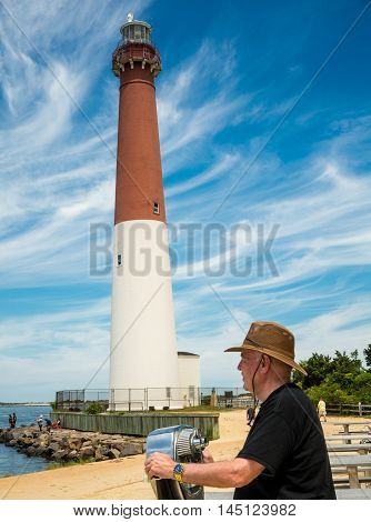 A Man with hat looking out the bay through the viewer at Long Beach Island