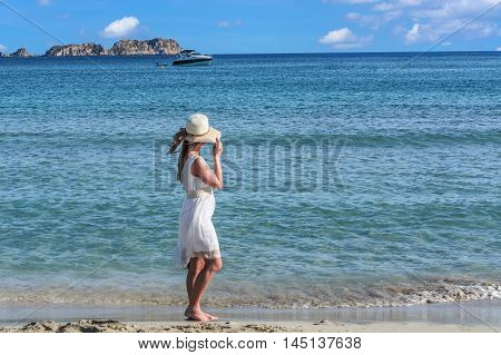 Young woman on the beach overlooking the sea in the background a motorboat.