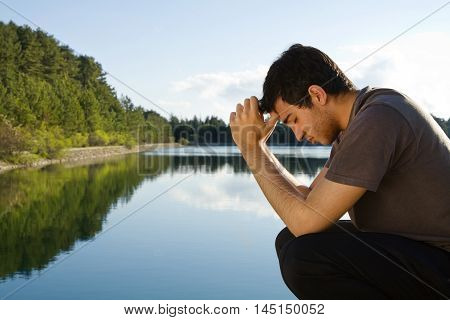 Man praying and meditating by beautiful lake
