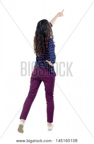 Back view of pointing woman. beautiful girl. Long-haired curly girl in a blue sweater pulled up.