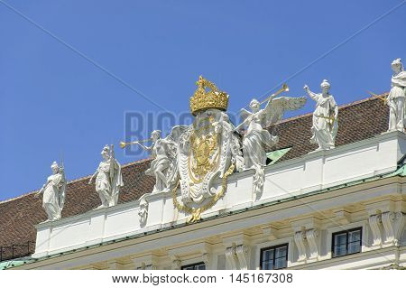 Statues on the roof of Hofburg Palace against the blue sky at sunny midday
