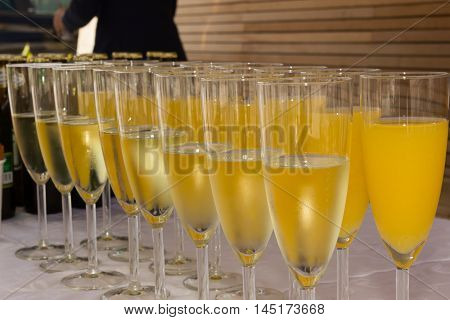 A Row Of Glasses Filled With Champagne And Orange Juice Are Lined Up Ready To Be Served