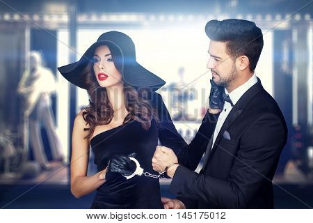 Sexy woman pulling rich man on handcuffs shopping at night