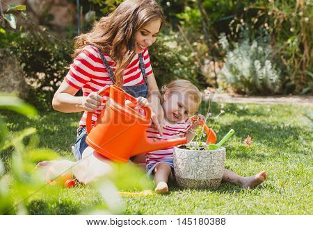 Pregnant woman with little daughter in the summer orchard cearing flower.