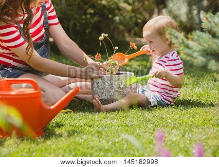 Pregnant woman with little daughter in the summer orchard cearing flower.