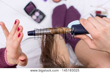 Woman Using Curling Iron On Her Hair
