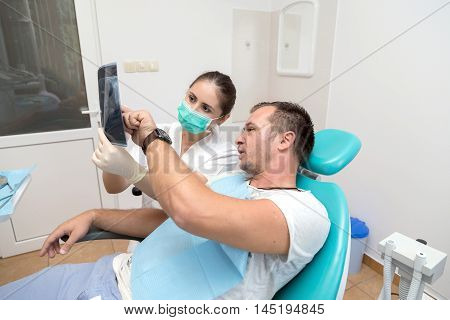 Image of young patient and dentist showing him x-ray radiography, in the Dental Clinc