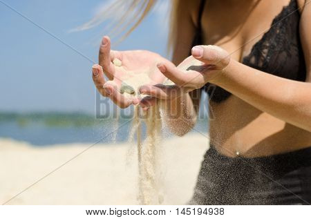 Young and happy model sow the sand trow her hands.
