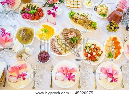 Beautifully decorated catering banquet table with different food snacks and appetizers with sandwich, caviar, fresh fruits on corporate party event or wedding celebration