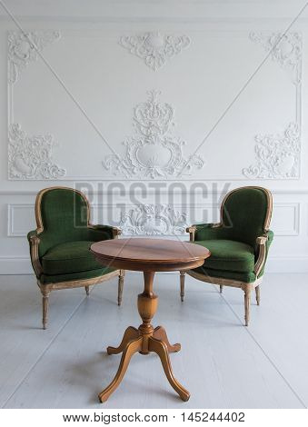 Luxury clean bright white interior with a old antique vintage green chairs over wall design bas-relief stucco mouldings roccoco elements.