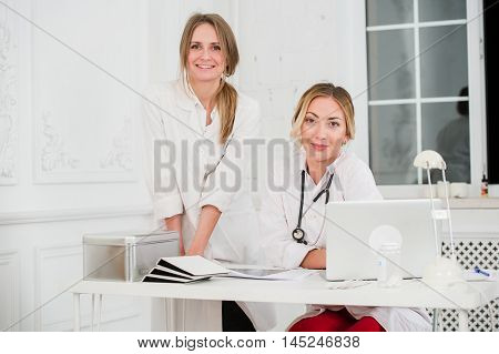 Two Female friendly cheerful Doctors or Nurses Isolated in office smiling and looking at camera.