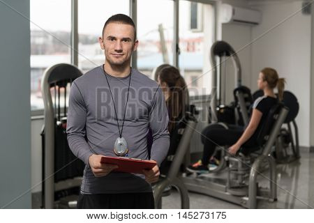 Personal Trainer Takes Notes While Woman Exercising Legs