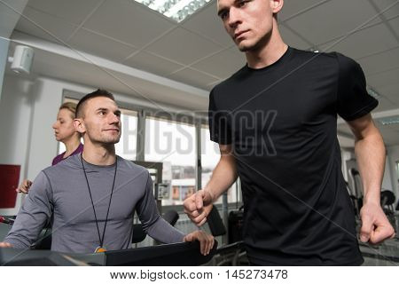 Personal Trainer And Client In Gym On Treadmills