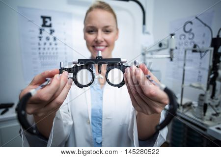 Portrait of smiling female optometrist holding messbrille in ophthalmology clinic