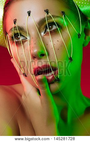 Woman with artistic make up in green and red lights. Studio photo. Extreme beauty style make up
