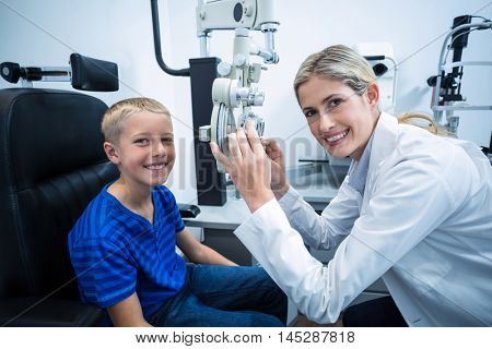 Female optometrist examining young patient on phoropter in ophthalmology clinic