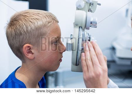 Young patient under going eye test through phoropter in ophthalmology clinic