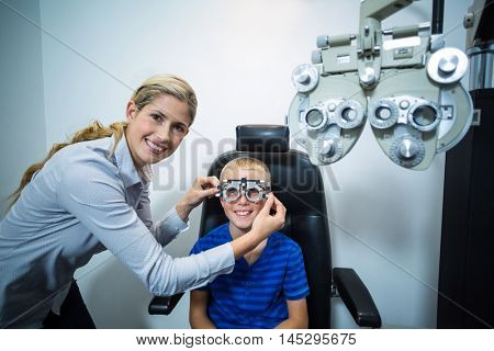 Female optometrist examining young patient with phoropter in ophthalmology clinic