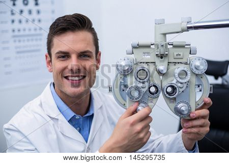 Smiling optometrist adjusting phoropter in ophthalmology clinic
