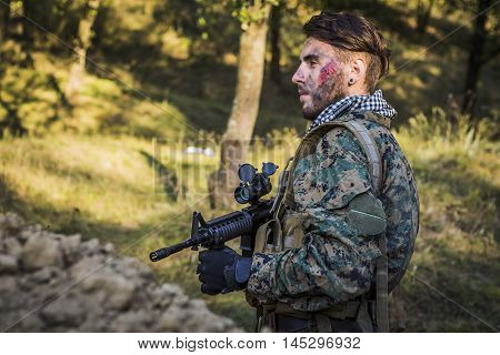 Soldier is waiting for battle in the forest with gun