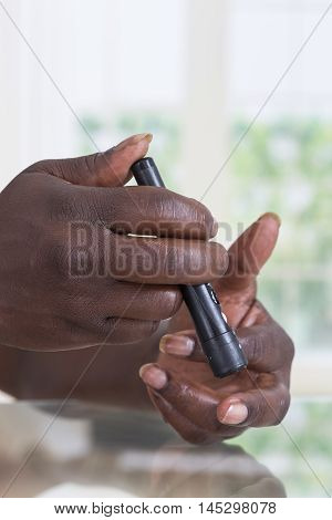 Hand of a woman using lancelet on finger