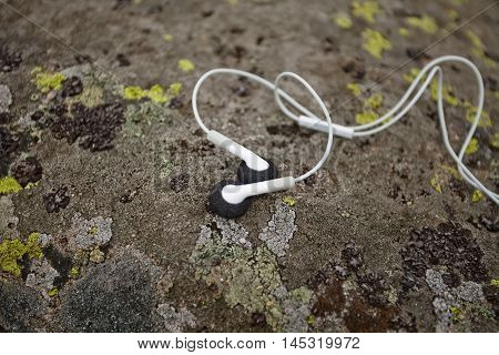 white earphones on moss-covered stone. Close up. Karpatian