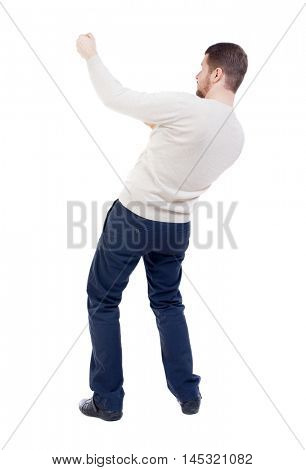 back view of standing man pulling a rope from the top or cling to something. bearded man in a white warm sweater pulls a rope from the top.