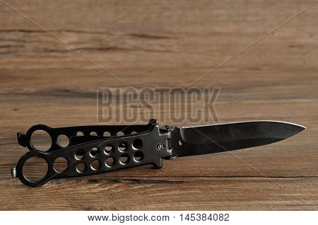 Steel butterfly knife (balisong) isolated on a wooden background