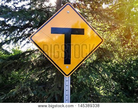 T intersection sign on tree background in the park