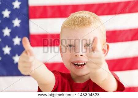 Little boy in front of American flag with thumbs up
