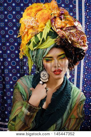 beauty bright woman with creative bright make up, many shawls on head like cubian, ethno look closeup