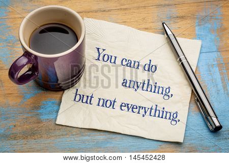 You can do anything, but not everything - handwriting on a napkin with a cup of espresso coffee