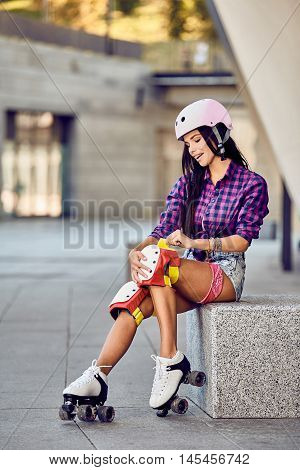 Active lifestyle girl is going to ride on roller skates. Stylish pink skating helmet, knee pads and quad roller skate.