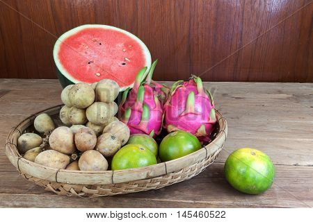 Asian fresh fruits. Langsat and watermelon and Orange and Dragon fruit in bamboo basket.